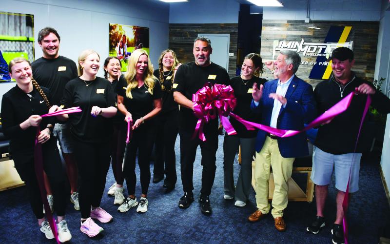 Greene County residents Dana and Dr. Pablo Santamaria (center, with scissors and bow) opened InMotion Wellness initially based on Pablo’s exposure to the benefits of targeted, assisted stretching after undergoing an operation to correct a painful back condition.