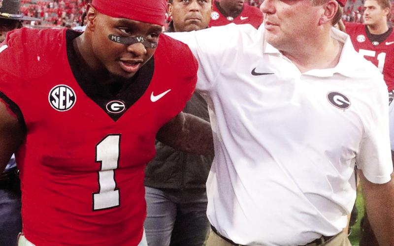 Georgia running back Trevor Etienne (left) shares a moment with head coach Kirby Smart (right) after the Bulldogs’ 31-13 win over Auburn. LANCE McCURLEY/Staff