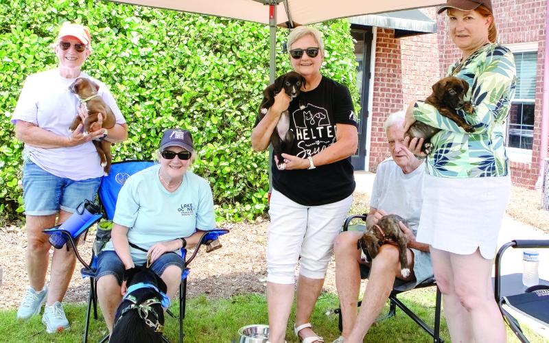 The volunteers of Lake Oconee Humane Society with 8-year-old Tripp and four of the puppies available for adoption. (LEIGH LOFREN/Staff)