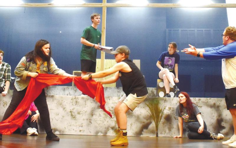 The “Godspell” cast practices a scene where conflict is shown through tug of war by the red curtain. BAILEY BALLARD/Staff