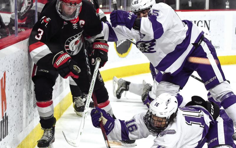 Ice Dawgs captain Evan Parante (3) fights off a pair of Niagara defenders to chase down a puck behind the Purple Eagles’ net Saturday night at Akins Ford Arena in Athens. IAN TOCHER/Staff