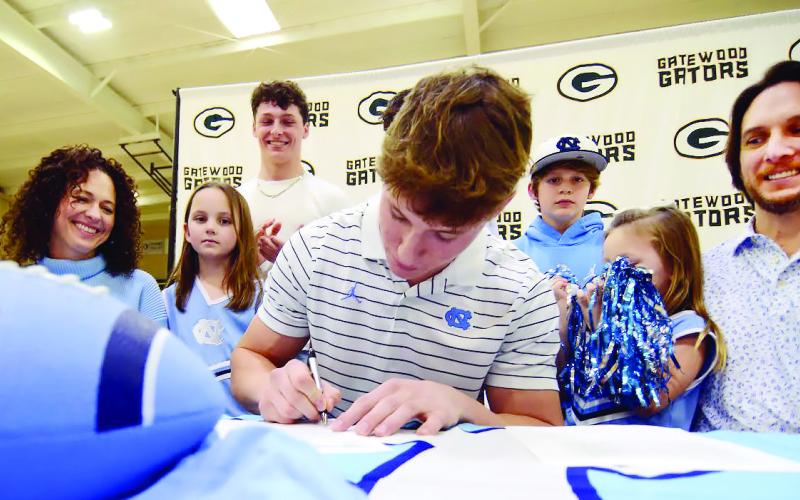 Surrounded by his family, including mother Christine and his father, Dan, Evan Bennett put pen to paper on his commitment contract with the University of North Carolina last Wednesday in Eatonton. IAN TOCHER/Staff