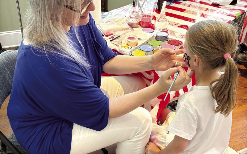 Five-year-old Evelyn Mallinson gets her face painted with a pink flower. (EMMA CLAUSE/Staff)