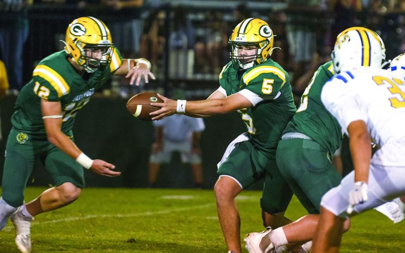 Filling in for injured quarterback Blake Brannen, sophomore Brady Haley (5) has been performing well, contributing a rushing touchdown against the Cavs, and shown here completing a handoff to junior running back Sean Bennett. IAN TOCHER/Staff