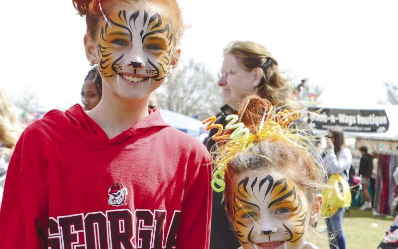 Abigail Jones and Macina McLean show off their new face paint designed by Happy Rainbow Creations.
