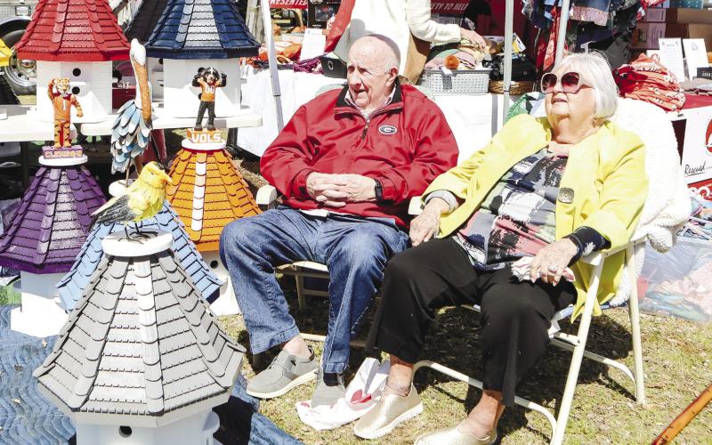 Woodie and his wife Carol Harper enjoy the sun in front of the stunning handmade birdhouses, that Woodie and his son-in-law make.