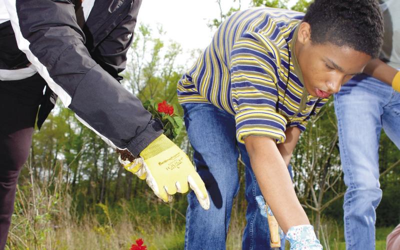 Volunteer Jonna Rubins Marchuk helps an APPLE student plant flowers at the Butterflies and Blooms habitat. IAN TOCHER/Staff