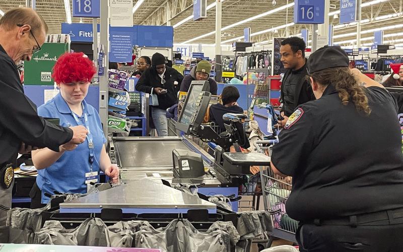 Eatonton Police Chief Howell Cardwell, right, pays the Walmart cashier as Investigator Hargrove Jones and Officer Rebecca Meeks load the purchases in carts during Shop with a Cop. LYNN HOBBS/Staff