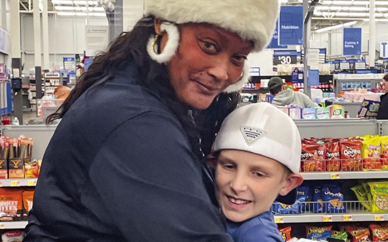 EPD Executive Assistant Tonya Thomas gets a hug from the child she shopped with. LYNN HOBBS/Staff