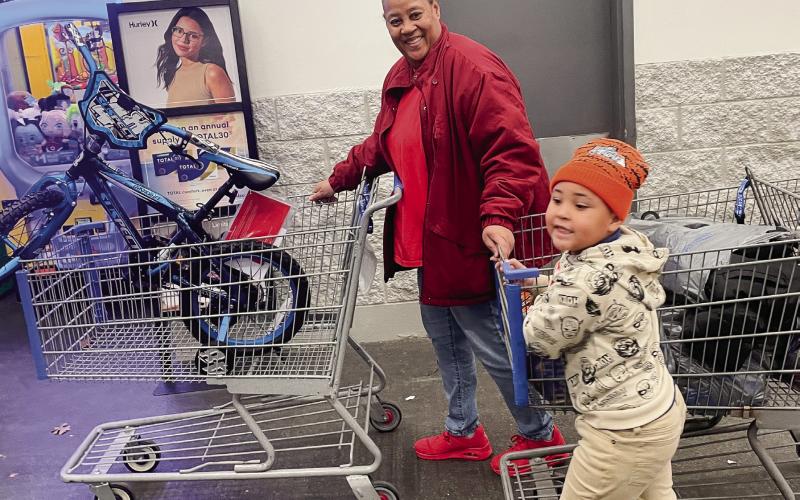 4-year-old Xavier Griffin helps his grandmother, Cassandra Solomon, push his filled shopping carts out the store after he shopped with a cop. LYNN HOBBS/Staff