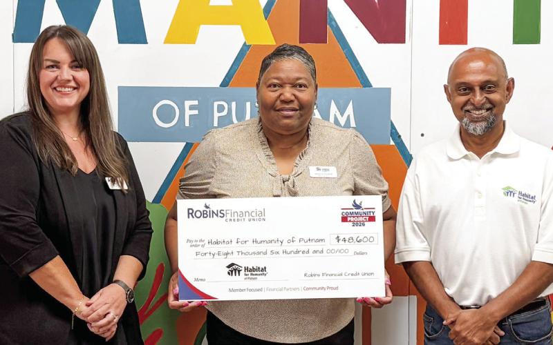 Habitat for Humanity of Putnam Executive Director Murali Thirumal (right) accepts a $48,600 grant check from representatives of Robins Financial Credit Union. CONTRIBUTED