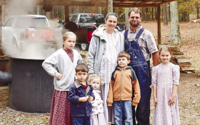 The Martin family, members of a Mennonite community in Dublin (l-R: Allison, Dustin, Ashley, Connie (mom), Waylon, Wesley (dad), and Kelly), pose in front of the pot where Wesley Martin cooked cane syrup at the event.