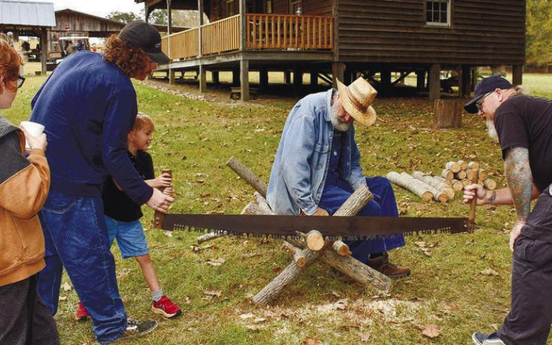 Practicing teamwork and wood-cutting skills are Andrew Esau (right) and his sons Jed and Joey, while another brother, Harry (left) and volunteer Rick Espelage are watching.
