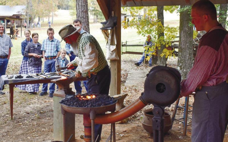 James Gardener (left) makes a knife as his son, Alex (right) is keeping an eye on bellows.