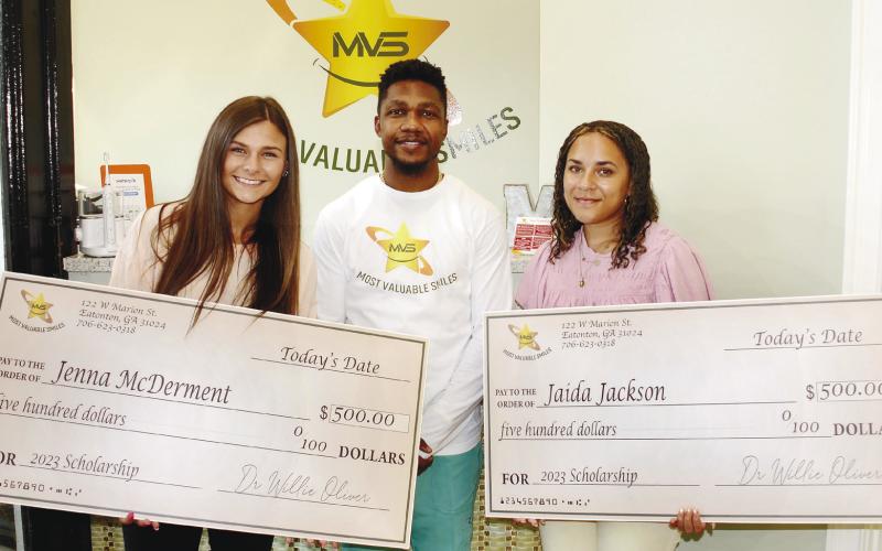 Dr. Willie Oliver of Most Valuable Smiles, presented Putnam County High School graduates Jenna McDerment (left) and Jaida Jackson with $500 scholarship checks last Friday. IAN TOCHER/Staff