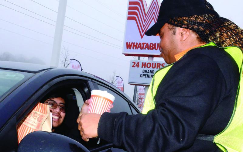 Whataburger employee Jaquana Pinkney delivers a free meal to Eatonton’s Stephen Munoz, who was first in line last Wednesday. IAN TOCHER/Staff