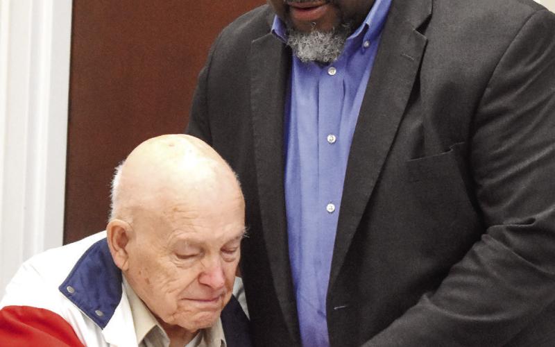 Superintendent Derick Austin (right) holds board member Eugene Smith’s hand as he offers his thanks for Smith’s many years of service to the school system. BAILEY MCCULLY/Staff