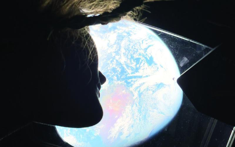 With her hair floating in near-zero gravity, NASA Mission Specialist Christina Koch gazes out at Mother Earth from a window on the Artemis II spacecraft. CONTRIBUTED
