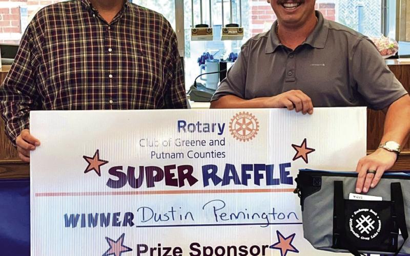 Keith Davis of Rotary Raffle sponsor Exchange Bank of Lake Oconee (left) delivers a “Cooler of Cash” featuring a $300 VISA gift card to Week 25 winner Dustin Pennington. CONTRIBUTEDw