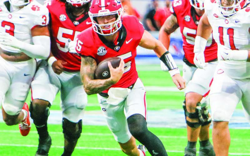 Georgia quarterback Carson Beck races past defenders for a first down. (LANCE McCURLEY/Staff)