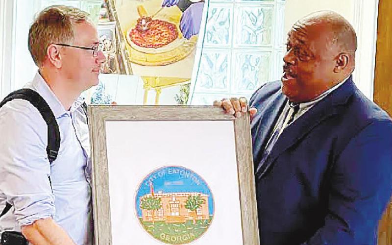 Mayor John Reid (right), presents a framed print of Eatonton City Hall to Mark Libell, chief of staff for Sen. Raphael Warnock. CONTRIBUTED