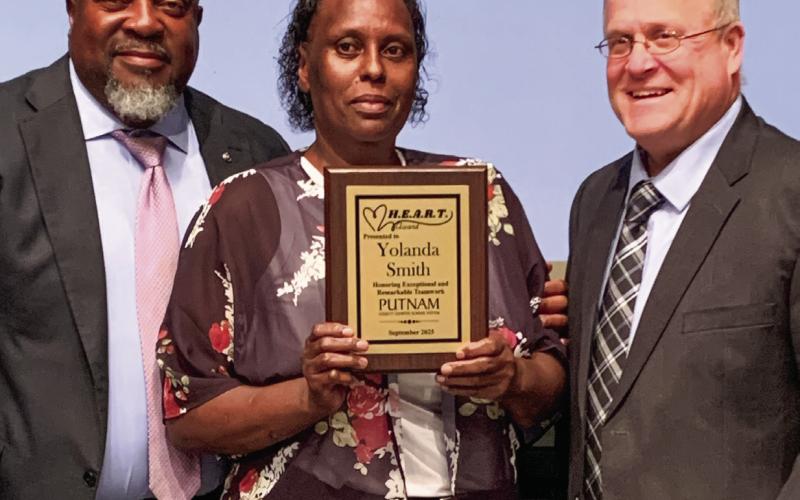 Superintendent Derick Austin (left) and Assistant Superintendent Scott Sauls present the HEART award to Yolanda Smith. BAILEY BALLARD/Staff