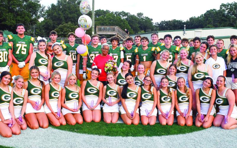 Gatewood cheerleaders and football players surround Eatonton icon Georgia Benjamin-Smith (in red) on her 85th birthday, following a brief pre-game candlelight vigil she organized to bring awareness to local domestic violence issues. IAN TOCHER/Staff
