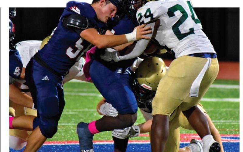 Despite losing his helmet, Gavin Aultman continues to help running back Kumari Thomas push forward for extra yards last Friday night against Aquinas. BRANDON PARK/Staff