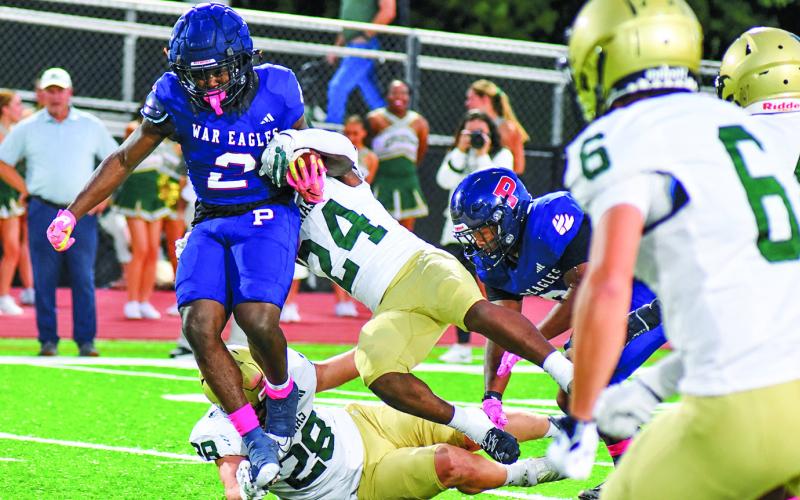 Putnam running back Kumari Thomas hurdles one Irish defender while breaking the tackle of another at home last Friday night against Aquinas. BRANDON PARK/Staff