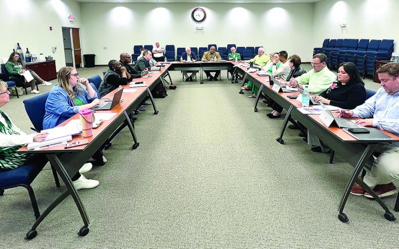 With Putnam County Chairman Bill Sharp (distant left) and Eatonton Mayor John Reid (center) seated side-by-side at the head of a U-shaped arrangement, elected members from both local government bodies debate the future and potential of a renewed SPLOST 10 initiative March 17 at the county administration building. IAN TOCHER/Staff