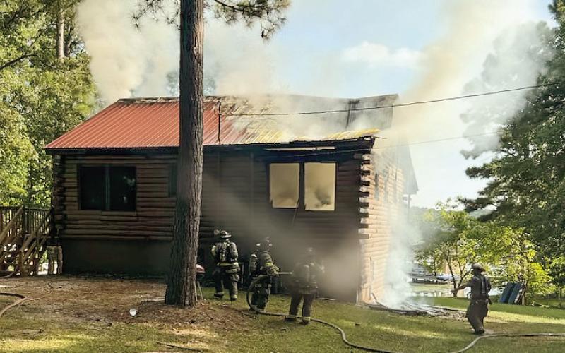 Putnam County Fire Dept. firefighters watch for flare ups amidst the smoke after putting out the flames of the fire in a log cabin on Rockville Springs Drive Monday. CONTRIBUTED