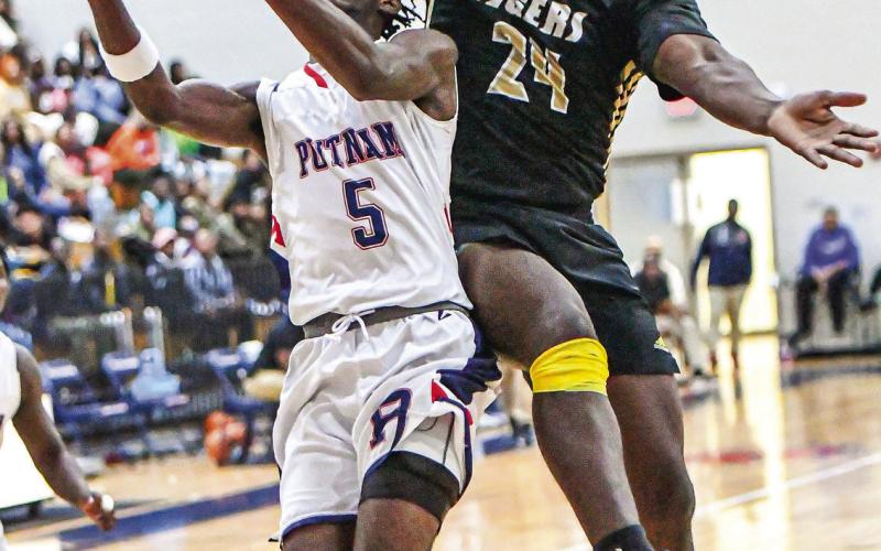 “Putnam County’s Jaylin Harper (5) goes up for a layup as Greene County’s RJ Monford (24) tries to block the shot. CHARLES JORDAN/Staff