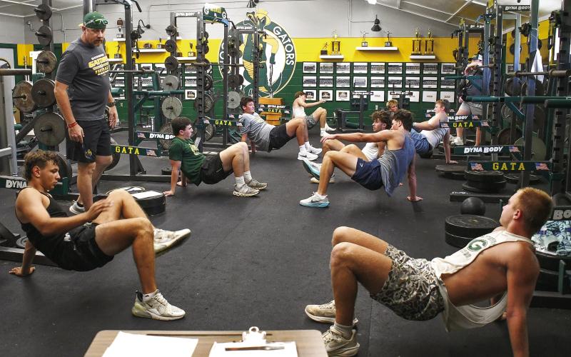 A group of veteran Gatewood football players goes through a drill in the weight room Tuesday morning, under the watchful eye of strength and conditioning coaches Scott Dennard and Conor Richards (far right). IAN TOCHER/Staff