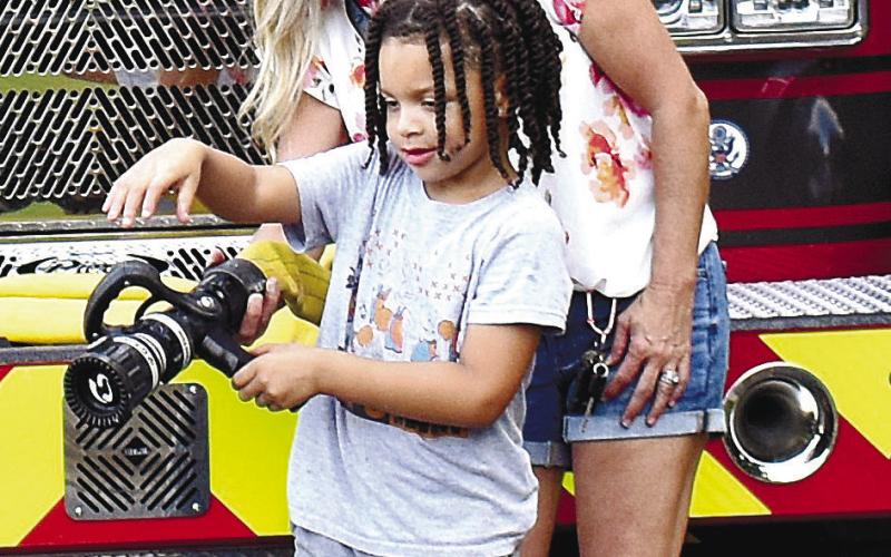 On the left, Kameren Green learns how to use a fire-hose, assisted by Wendy McClain, who is part of the firefighters’ squad in nearby Henry County.