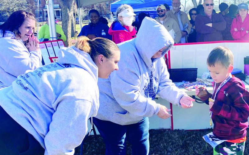 From left, Ashley, Zoey, and Denise Monica congratulate 5-year-old C. Millwood of Eatonton, winner of the 5K’s male 10 and under category. LYNN HOBBS/Staff