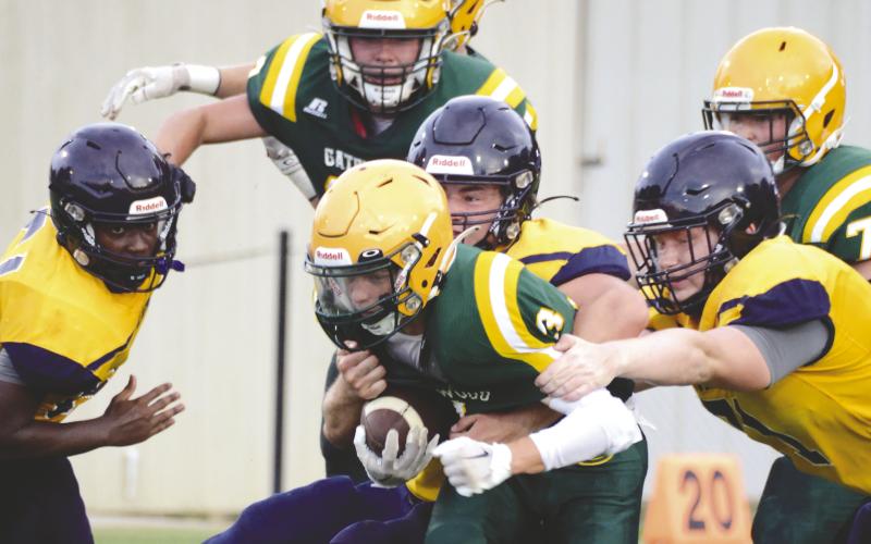 Junior running back Jackson Hewatt (3) is the center of attention of teammates and rivals alike in a first-quarter scrimmage run Friday night at Gatewood Schools in Eatonton, versus the Cavaliers of Mount de Sales Academy. IAN TOCHER/Staff