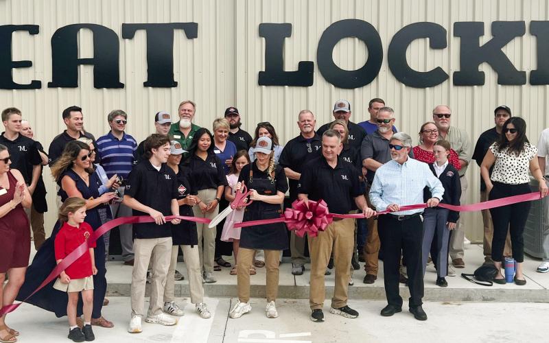 Lisa Simmons, co-owner of The Meat Locker with her husband Darin beside her, makes the official ribbon cut April 4 with Eatonton-Putnam Chamber of Commerce President Robbie King (in sunglasses) looking on. IAN TOCHER/Staff