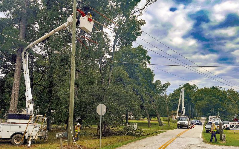 Crews work on downed limbs and power lines at the intersection of North Maple Avenue and Madison Road at the north end of Eatonton. IAN TOCHER/Staff