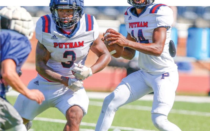 Putnam County quarterback Caleb Reeves (14) drops back in the pocket with running back Elijah Dunn (3) providing pass protection during a padded camp in Eatonton last month. LANCE McCURLEY/Staff