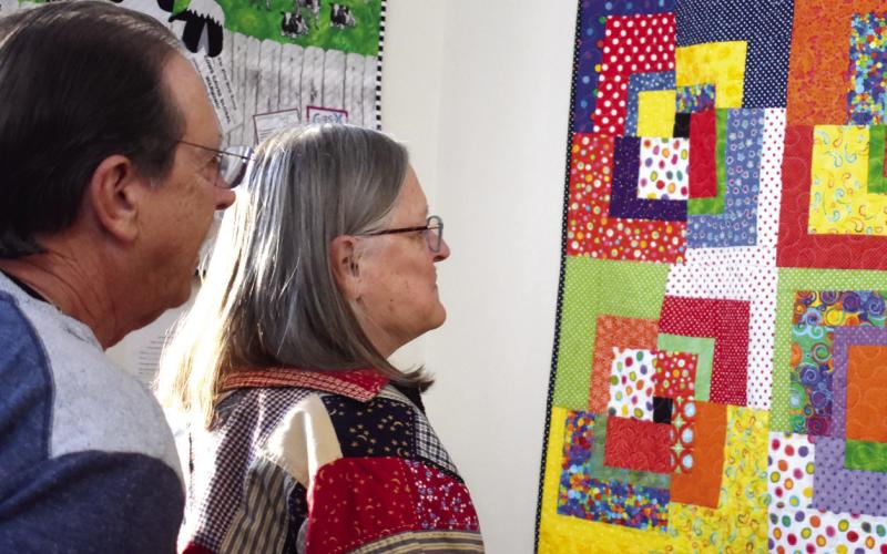Two attendees of the opening reception view one of the largest quilts in the exhibit room. BAILEY MCCULLY/Staff
