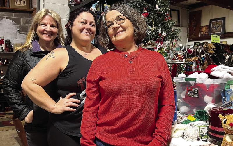 Veterans Thrift Store manager Nikki Barker (center) is flanked by employees Gina Thomason (left) and Phyllis Campbell in front of a special Christmas decorations section of the store.