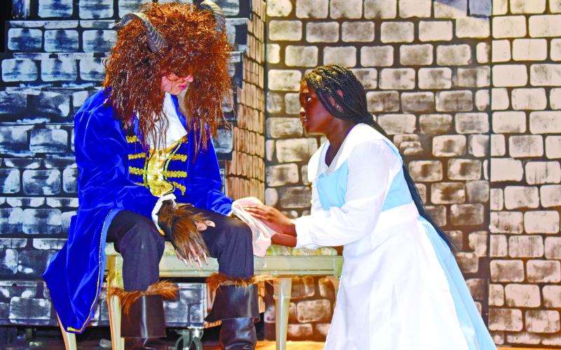After Beast, played by Avry Shorter, is injured by wolves, Belle, played by Kenzie Nelson, cleans his paw.