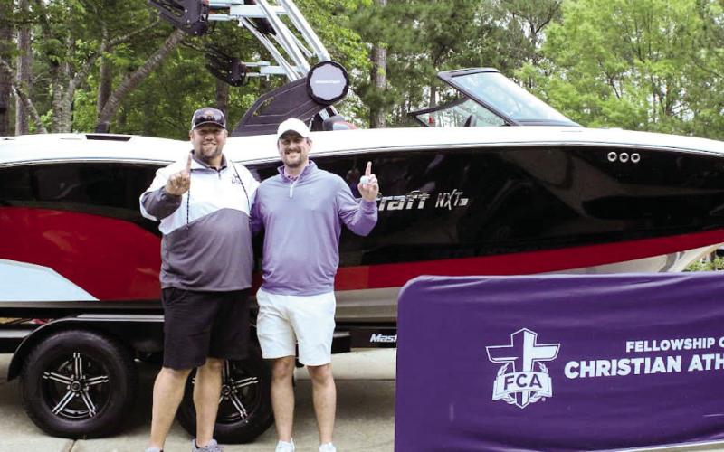 Lake Oconee FCA Area Director Jason McBay (left) and tournament Jeremy Britt (right) pose for a photo in front of the Mastercraft boat that Britt won after a hitting a hole-in-one on No. 13.  (CONTRIBUTED)