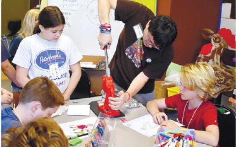 Noel Schornhorst stamps a button for Sydney Kornegay as other kids wait for their turn.  LENA HENSLEY/Staff