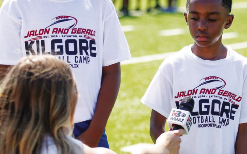 Left: A camper runs over tackling dummies while securing the football during a drill. Right: Two campers are interviewed by a reporter from 13WMAZ in Macon.