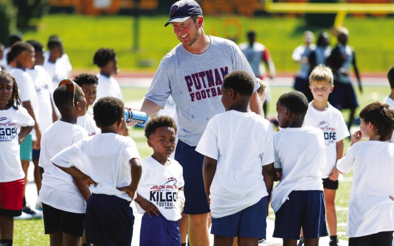 Current Putnam County head football coach Joel Harvin hands out water to campers during a break in the action.