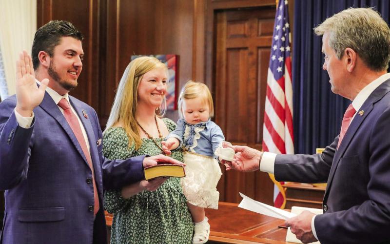 Putnam County Clerk of Courts Trevor Addison (left), with his wife Pelar (pronounced “Pil-arr”) holding a family Bible, was sworn in Feb. 25 by Georgia Governor Brian Kemp while the governor was holding the hand of Addison’s young daughter, Cora Rose. CONTRIBUTED