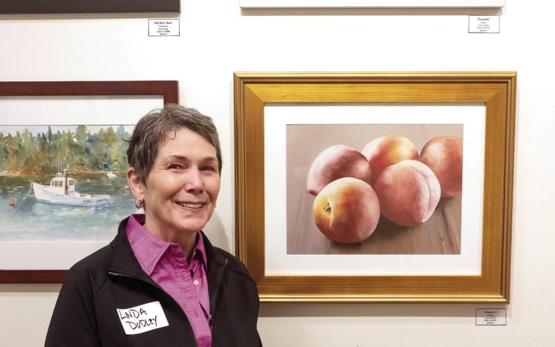 With two of her pastels, Linda Dudley is all smiles at the exhibit Wednesday evening. LEIGH LOFGREN/Staff