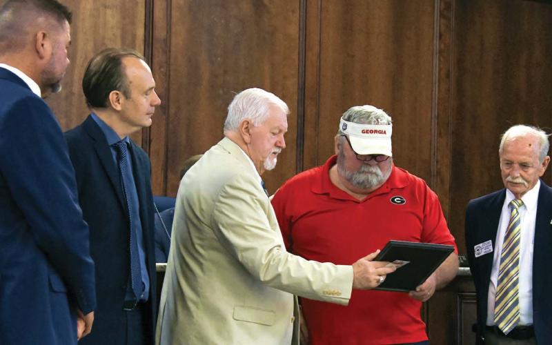 L-R: Putnam County Commissioners Tom McElhenney and Richard Garrett watch as Chairman Bill Sharp shows a proclamation recognizing the retirement of Torrey Whittaker after 20 years of county service, with Commissioner Steve Hersey looking on. IAN TOCHER/Staff