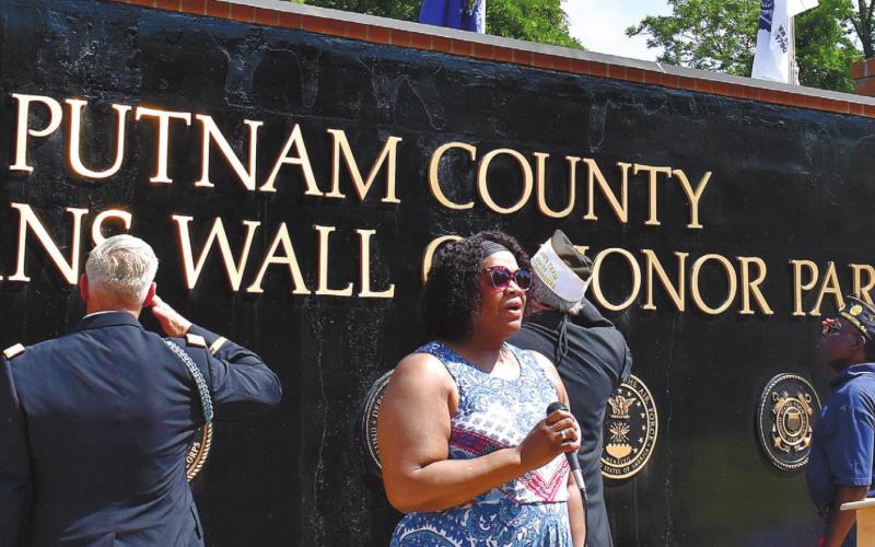 Loretta Hampton sings the Star Spangled Banner while those attending the Memorial Day ceremony at Veterans Wall of Honor Park salute the American flag. T. MICHAEL STONE/ S t a ff